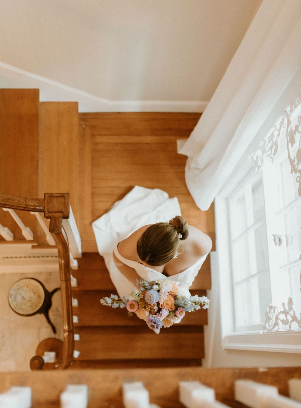 Delicate white curtains flutter in front of a rustic wooden window frame creating a soft, romantic ambiance.