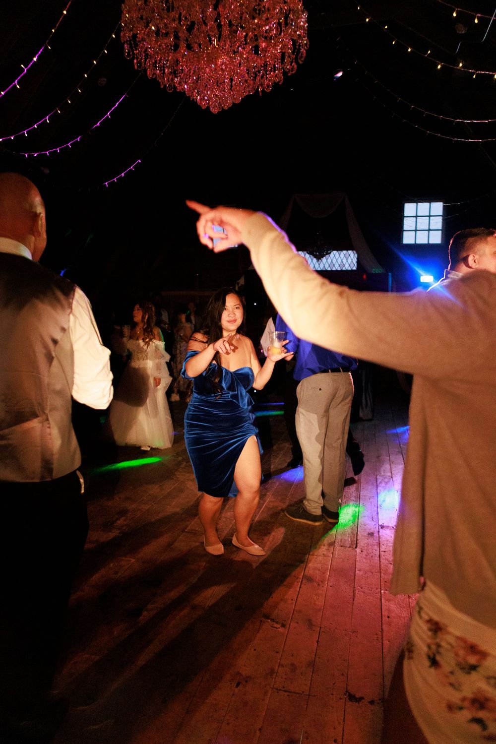 People dancing at a dimly lit party with colorful lights and decorations overhead.
