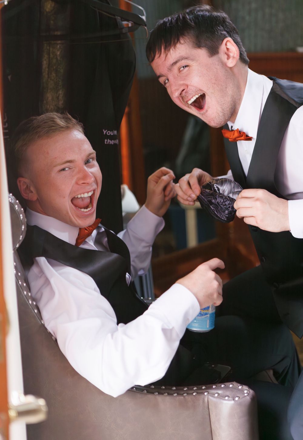 Groomsmen in formal attire laughing and having fun during candid wedding party photos.