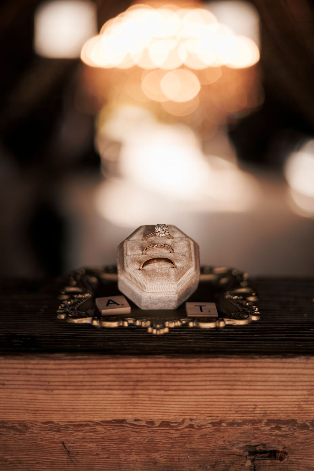 Wedding rings displayed on a rustic wooden surface with soft bokeh lighting in the background.