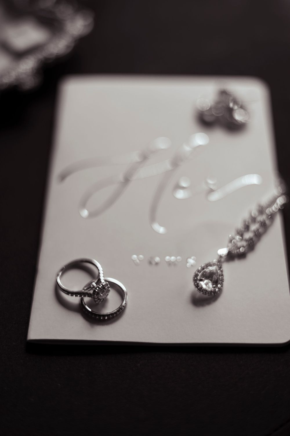 Close-up macro shots of diamond rings and jewelry on a white surface in black and white.