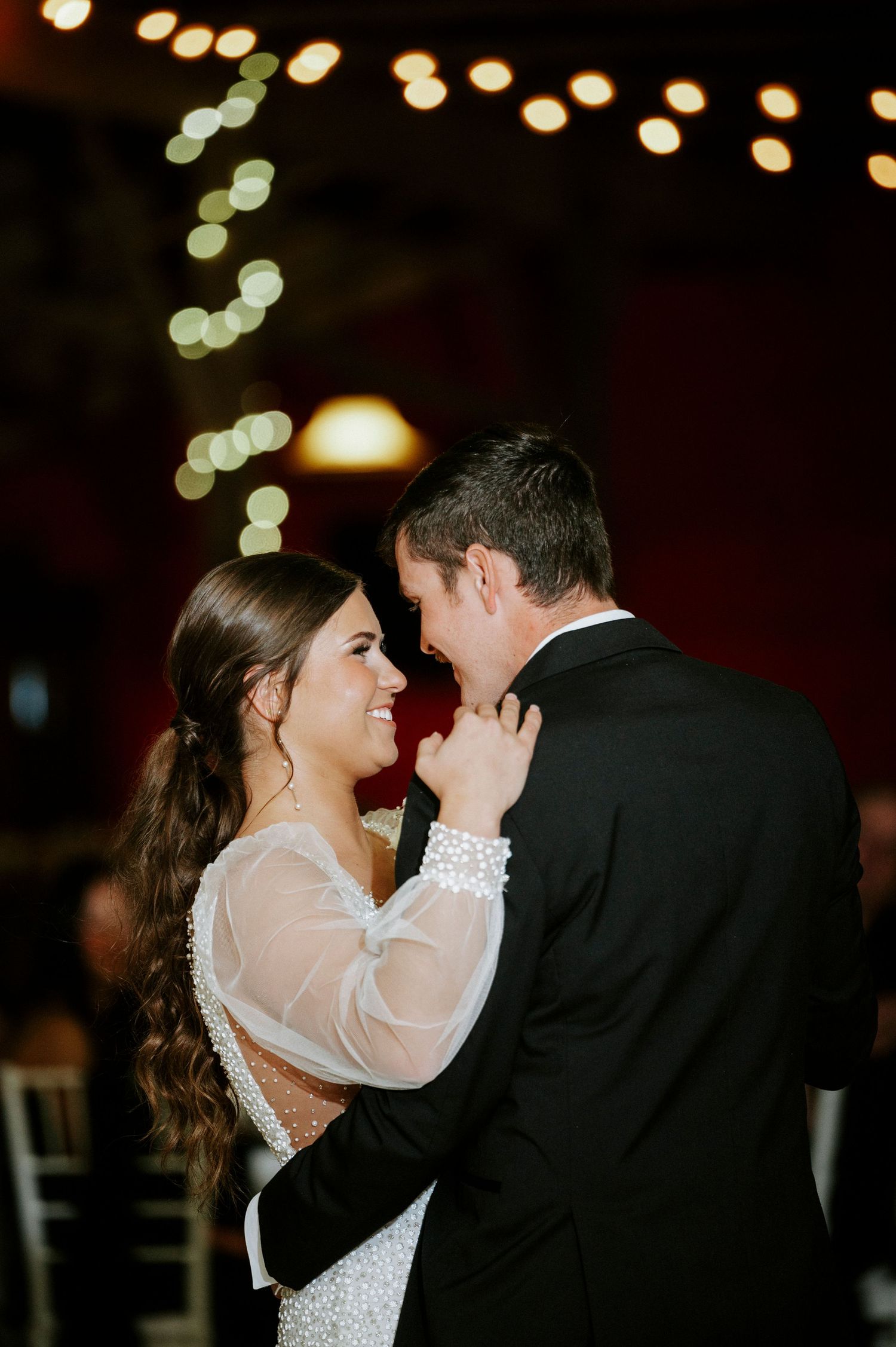 A romantic wedding dance moment under twinkling string lights at an evening reception.