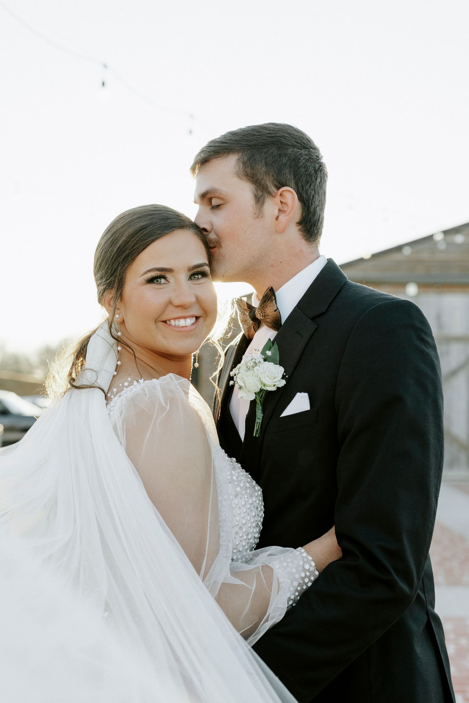 A romantic moment captured between a couple on their wedding day with soft lighting and elegant attire.