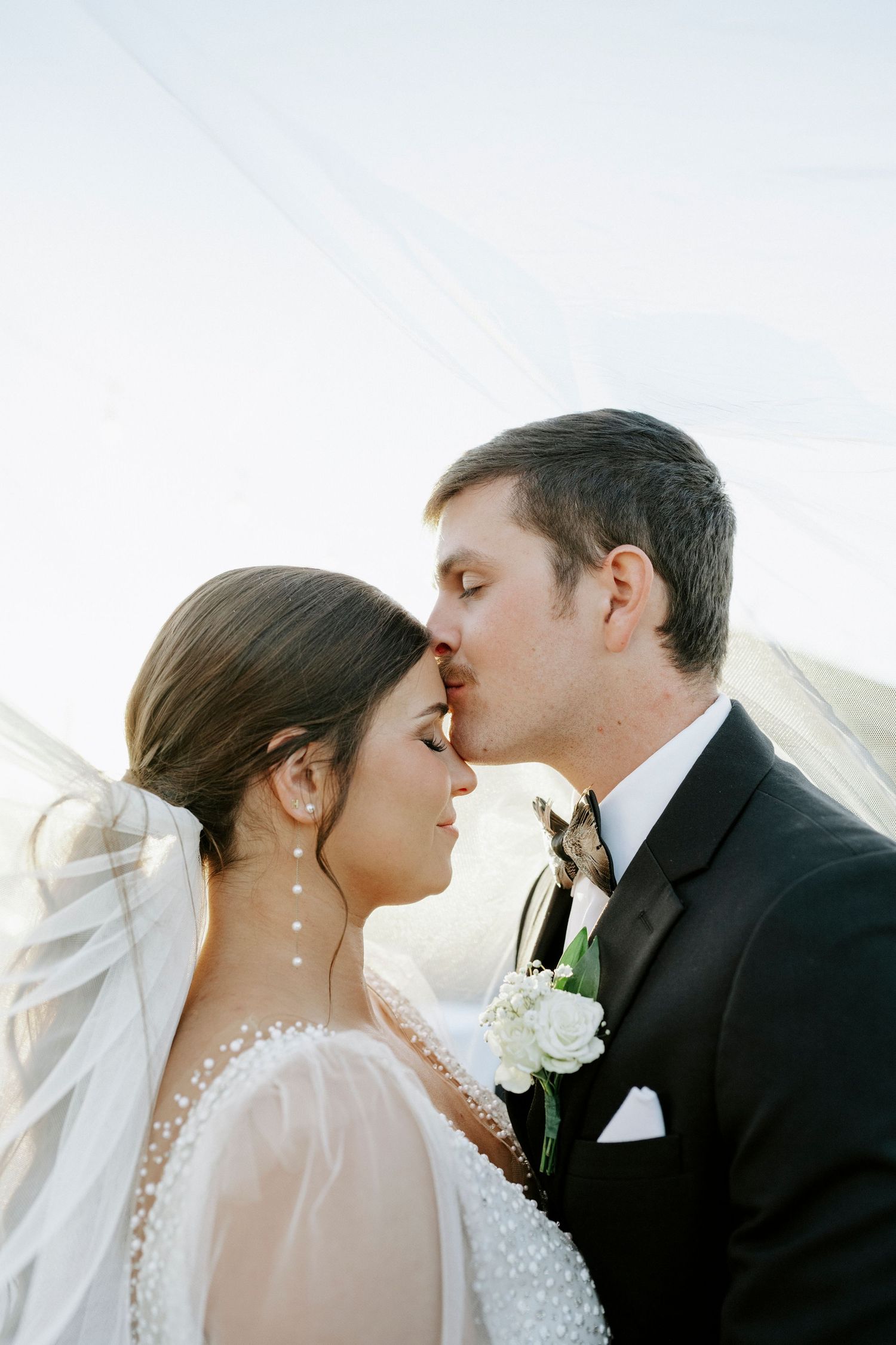 Romantic wedding couple shares tender kisses in a series of soft sunlit portraits.