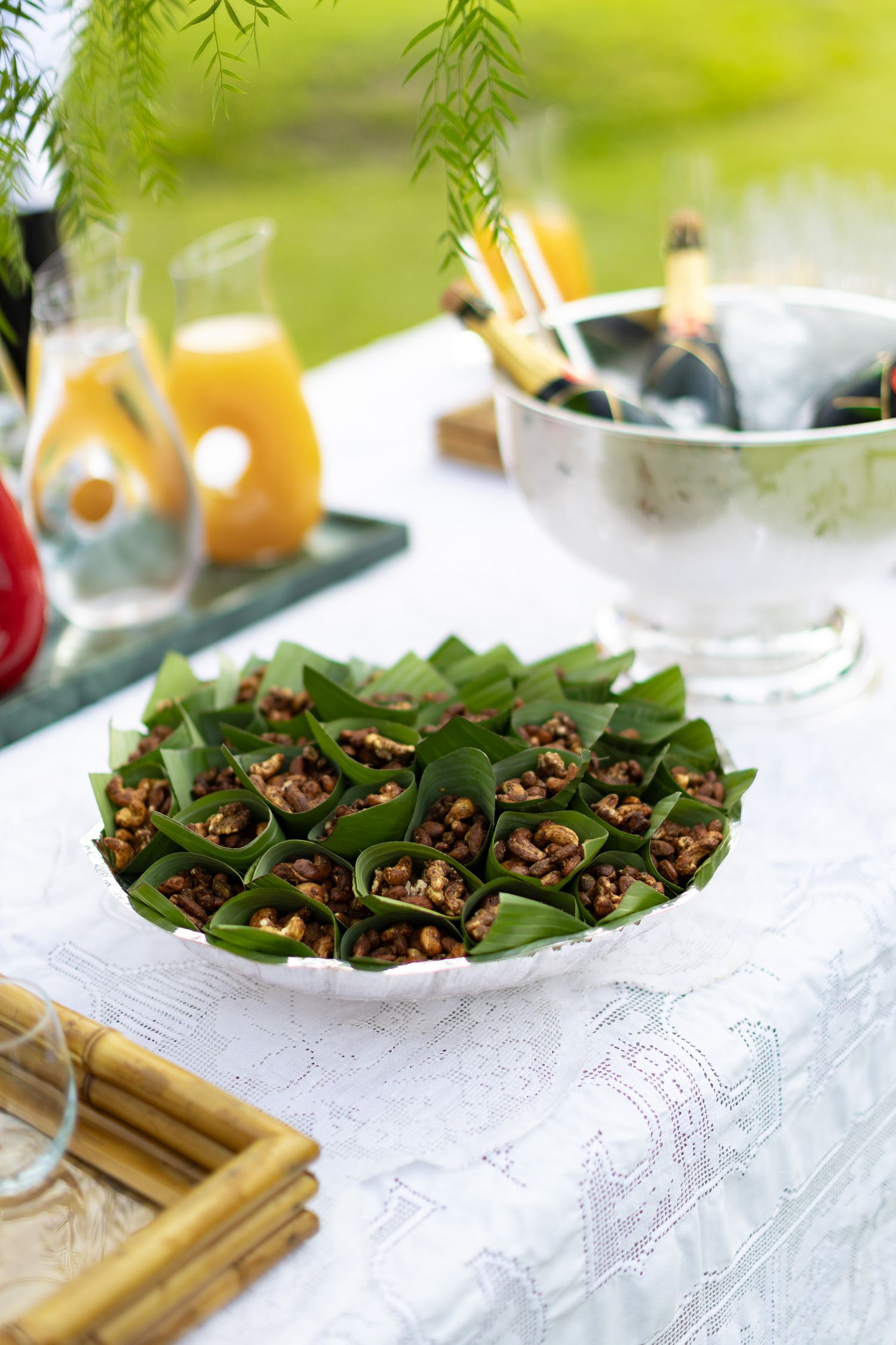 Fresh appetizers served on lettuce leaves arranged on a white lace tablecloth with bamboo serving utensils.