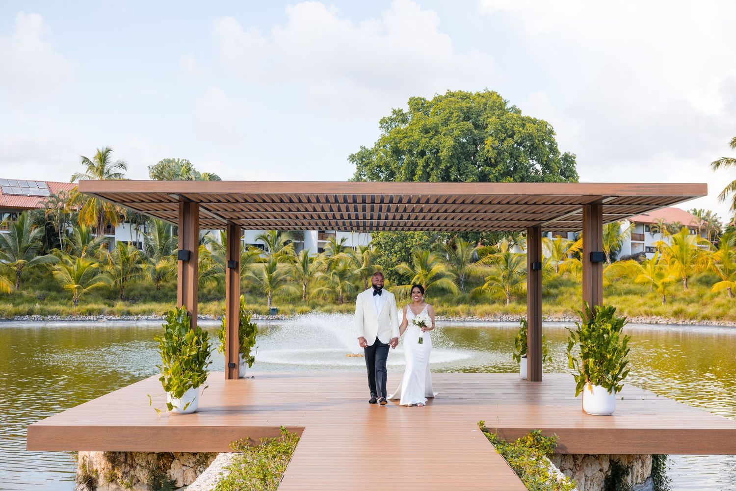Outdoor wedding venue with covered walkway and palm trees overlooking a waterfront setting. Casa de Campo Hotel Resort Spa