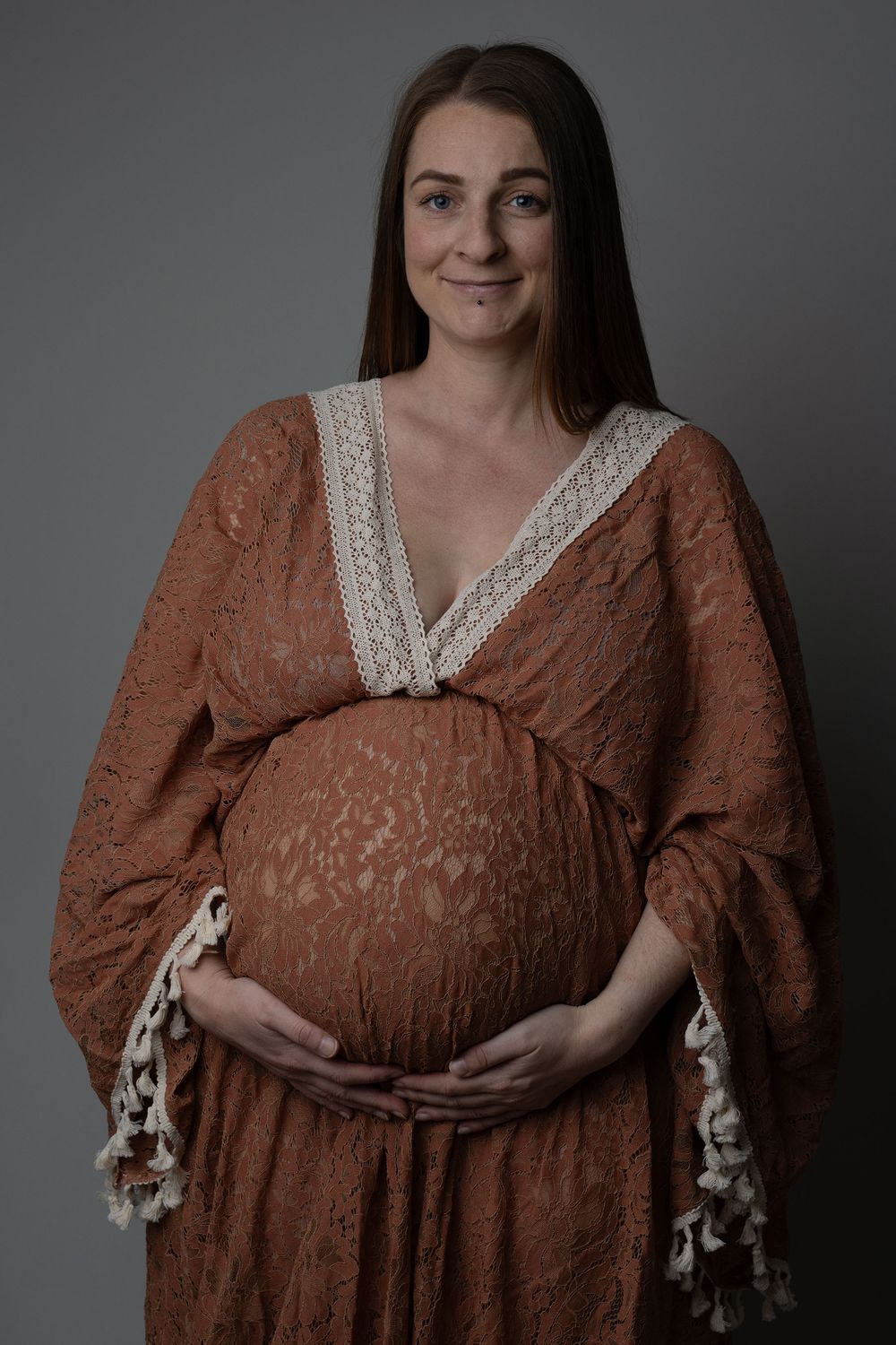 Pregnant woman posing in a beautiful, rust, boho gown during an in-home maternity photoshoot in Ceredigion