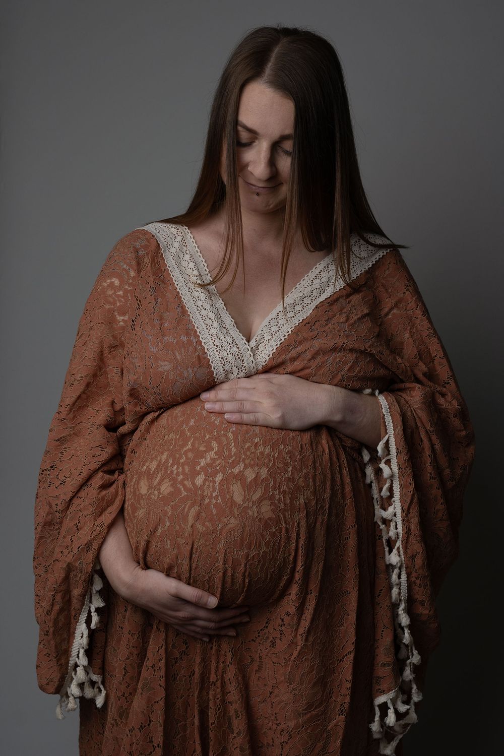 Pregnant mother wearing a rust, boho gown during an in-home maternity photoshoot in Ceredigion
