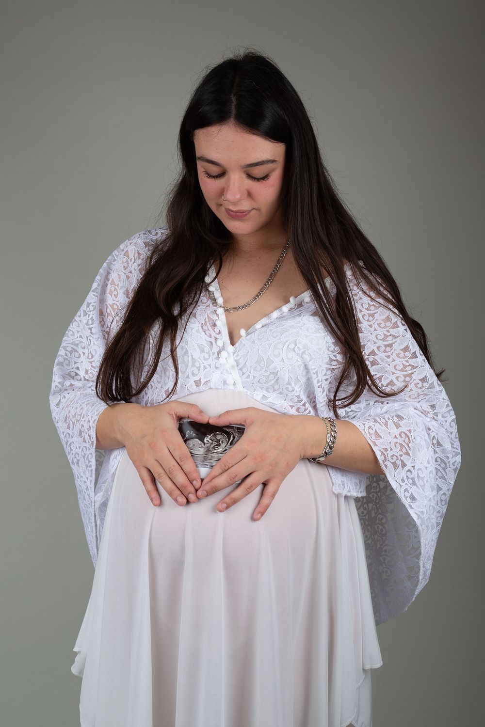 Mother looking down at baby bump with baby scan over the top, captured during a relaxing photoshoot in Ceredigion