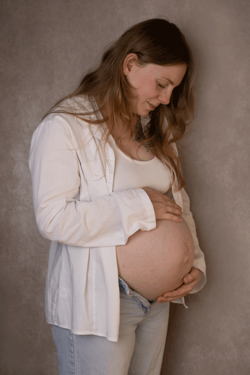 Expecting mum looking down at baby bump during Ceredigion in-home maternity photoshoot