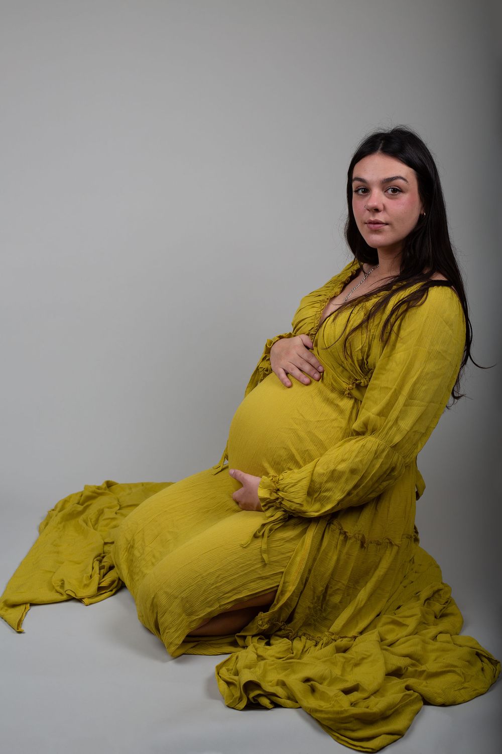 Expectant mother wearing a lime green boho gown during an in-home maternity photoshoot in Ceredigion