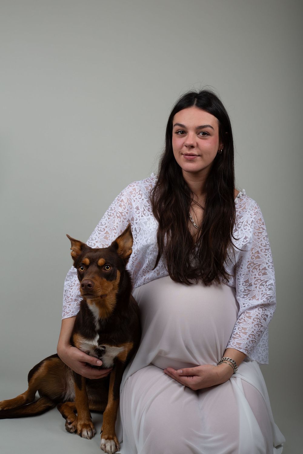 A pregnant mother posing on her knees next to her dog during a maternity photoshoot in West Wales
