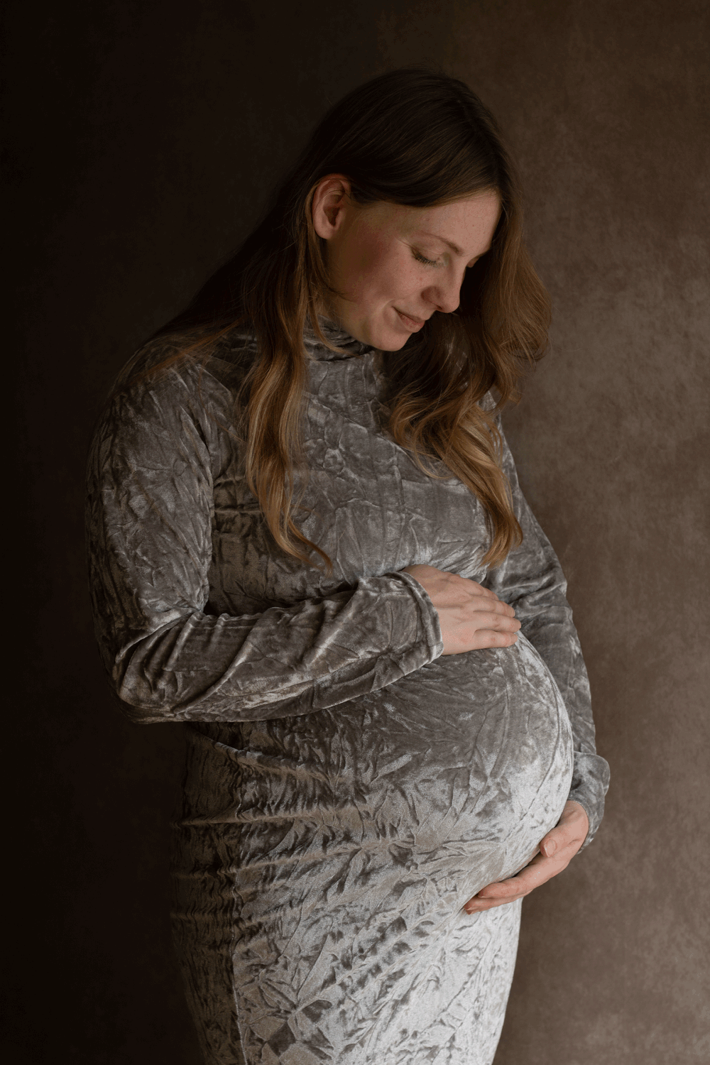 Pregnant mum wearing a grey velvet dress during a relaxing maternity session in Ceredigion