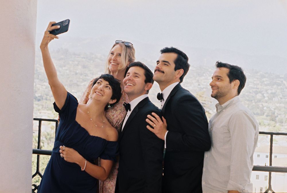 Two grooms take photos with their friends at the Santa Barbara County Courthouse