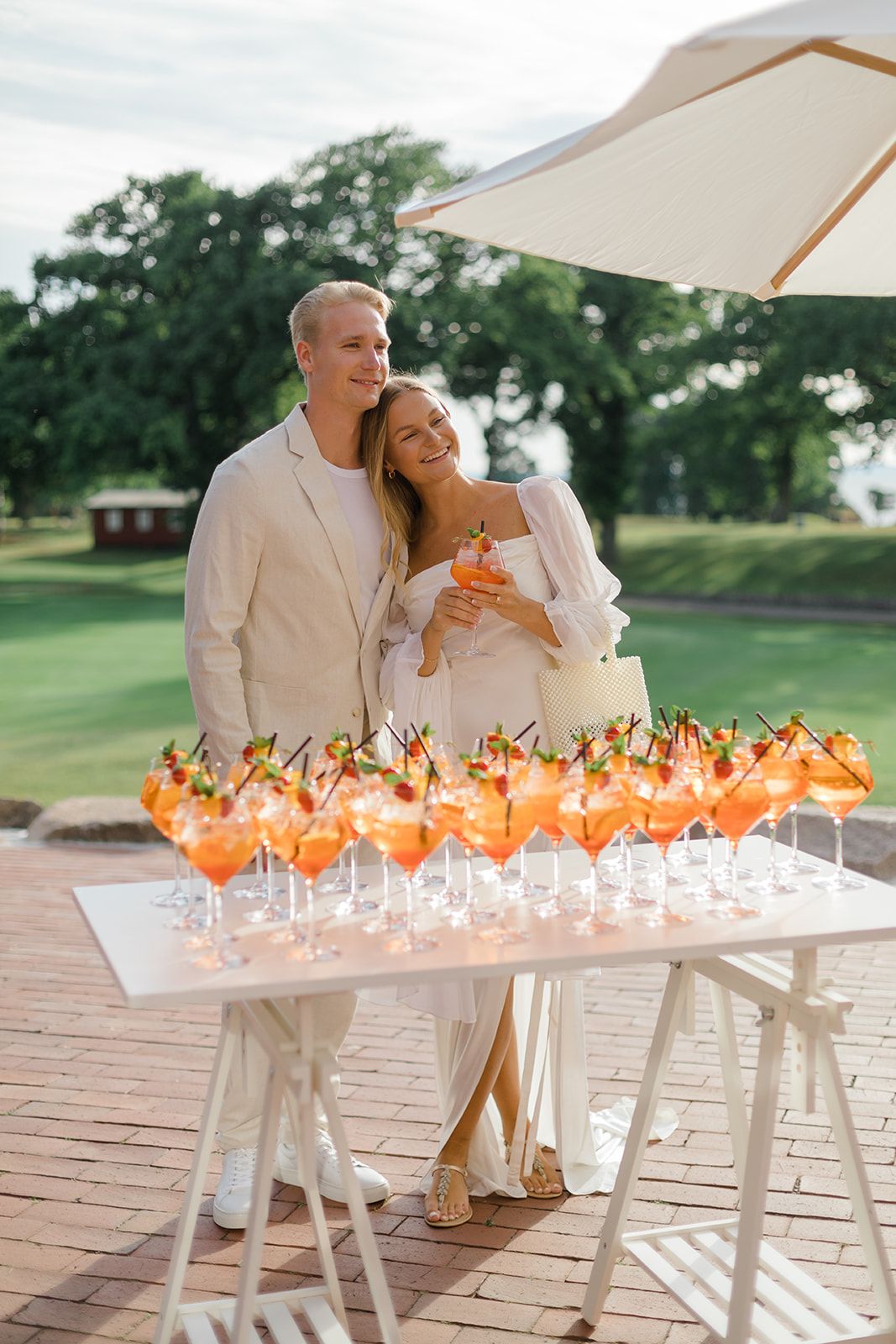 A couple embraces near an illuminated table display of glowing orange butterflies on a patio at dusk.