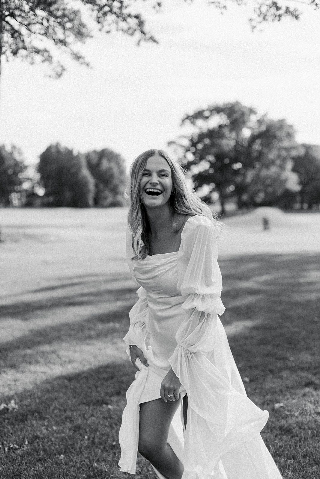 Black and white photo series showing joyful moments in a white dress on a grassy hillside during golden hour.