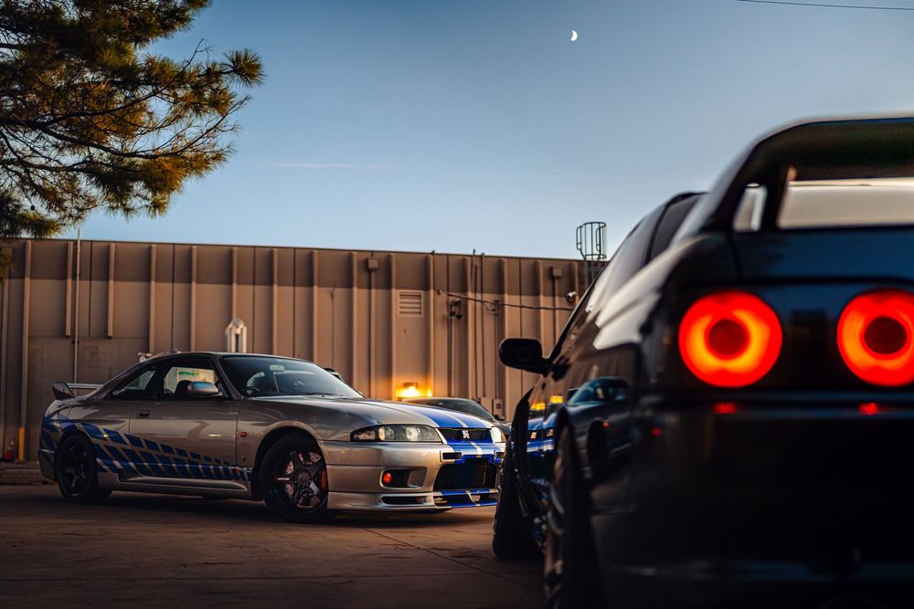A series of car detail shots showing tail lights and body panels against a sunset sky background.