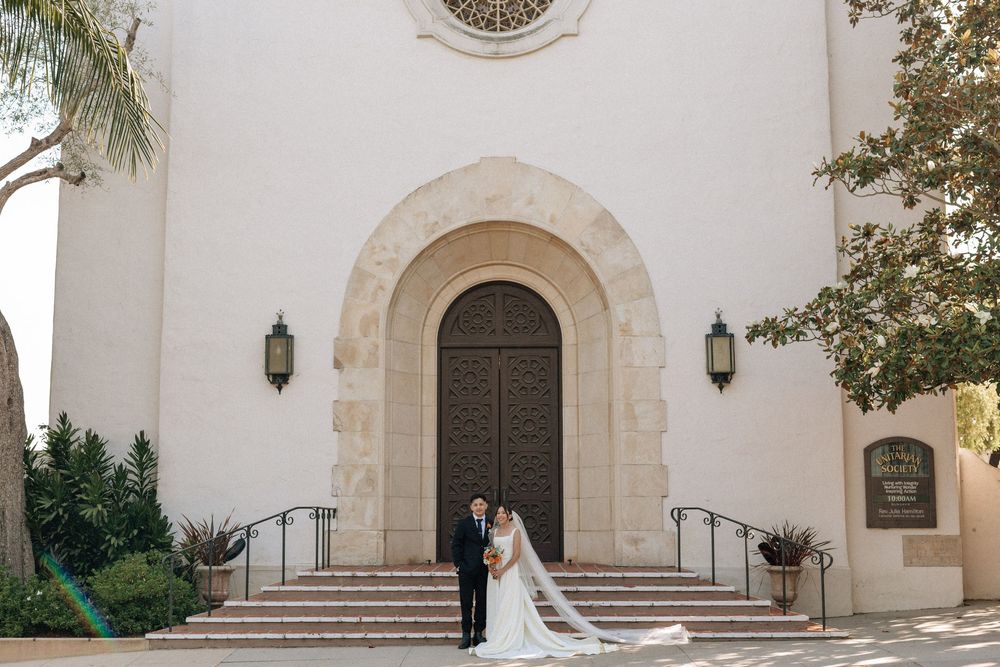 Elegant portrait of the couple standing in front of the impressive Spanish Revival architecture facade of the Unitarian Society.
