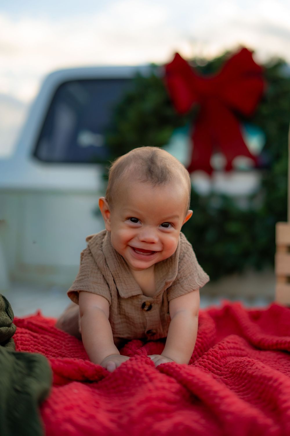 Family enjoying a festive Texas farm Christmas mini session, sitting on the bed of an old red Ford truck decorated with holiday greenery.