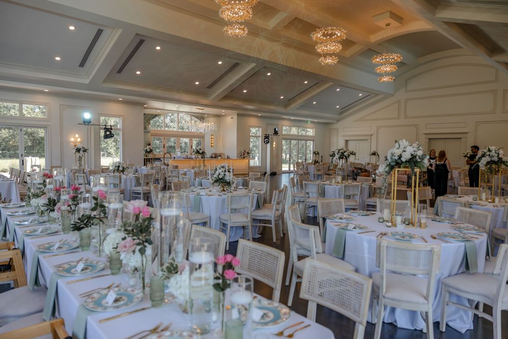 Elegant ballroom setup with white linens, crystal chandeliers, and floral centerpieces for a luxurious wedding reception.