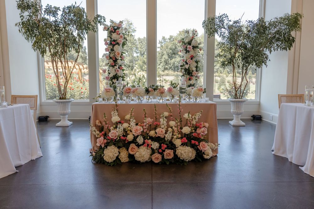 Elegant wedding venue interior with white curtains, floral arrangements and natural light streaming through large windows.
