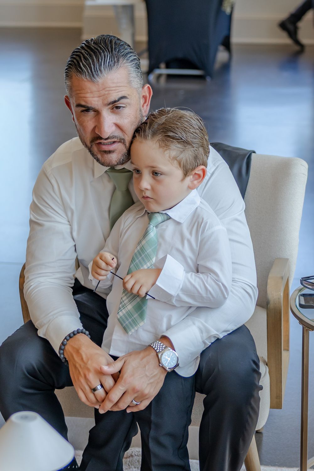 A touching moment between a father and young boy in formal white shirts sharing an emotional embrace.