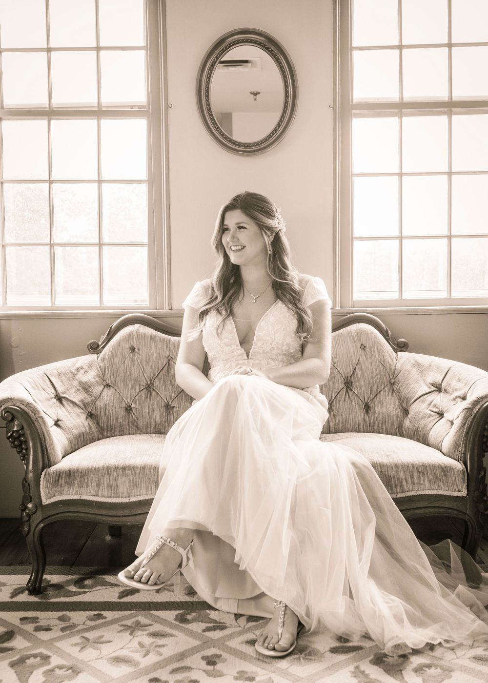 Vintage white sofa with ornate details set against a bright window-lit room.