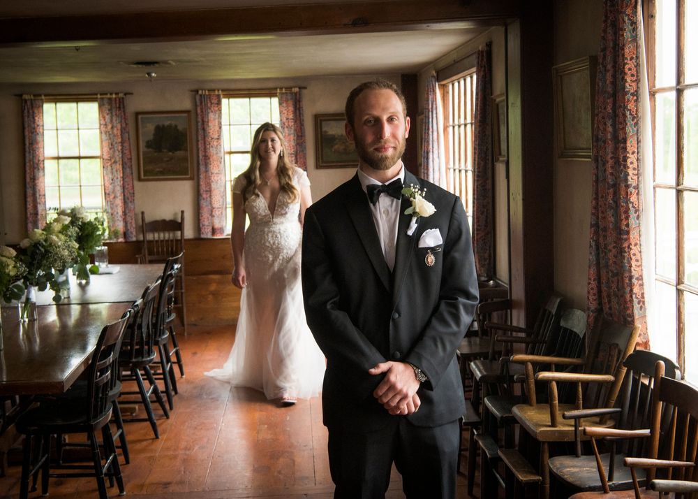 Wedding party poses in an elegant indoor venue with large windows and wooden floors.