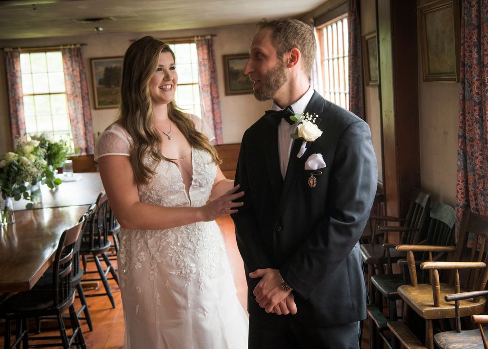 Wedding couple sharing an intimate moment in a rustic indoor setting with natural window light.