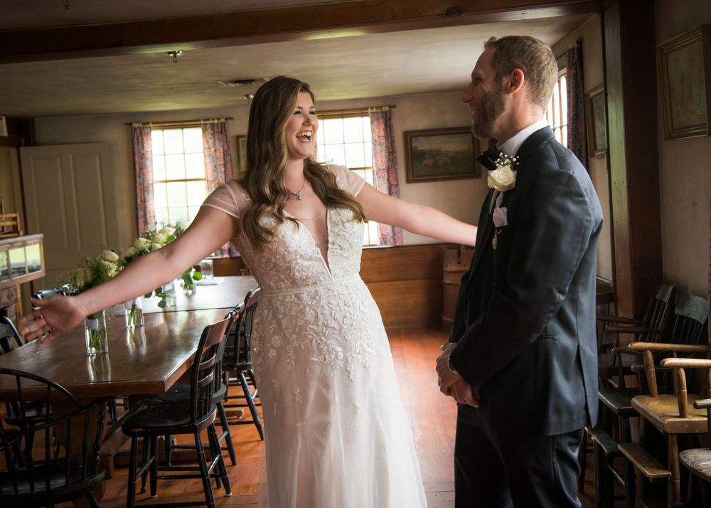 A couple shares their first dance in a rustic barn venue with wooden beams and natural lighting.