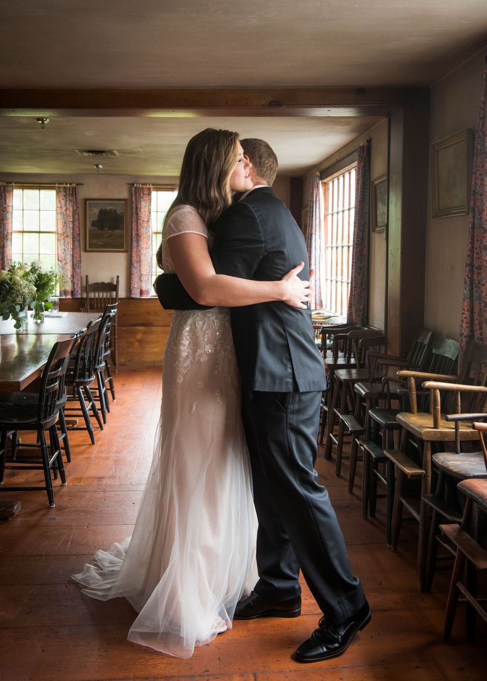 A romantic first dance sequence in a rustic indoor venue with wooden floors and natural lighting.
