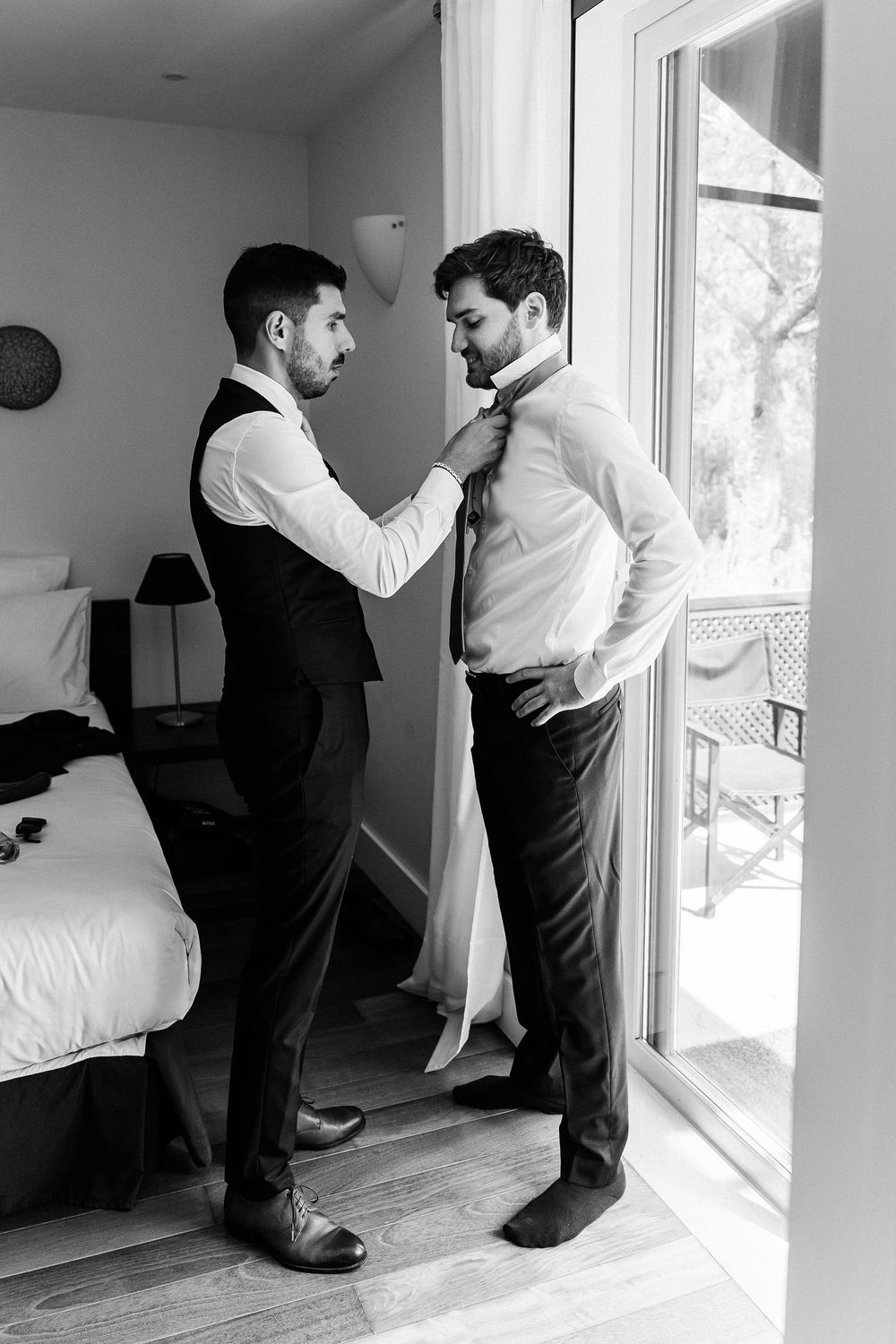 Black and white photo series showing two people in formal attire helping each other get dressed for a formal event.