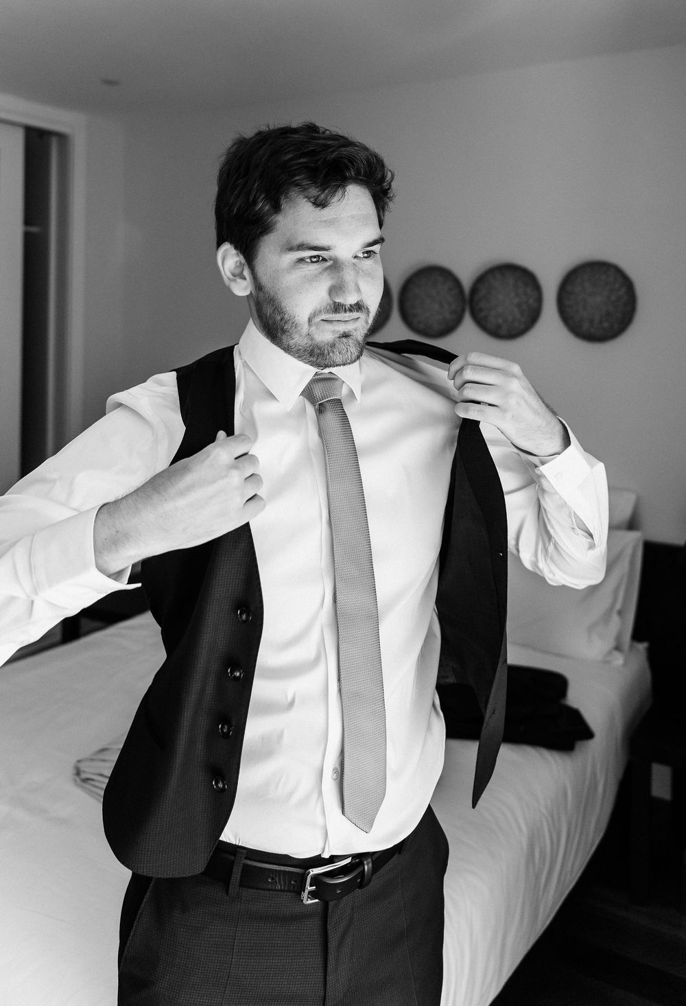Black and white photo sequence showing a person adjusting their tie and collar while getting dressed in formal attire.