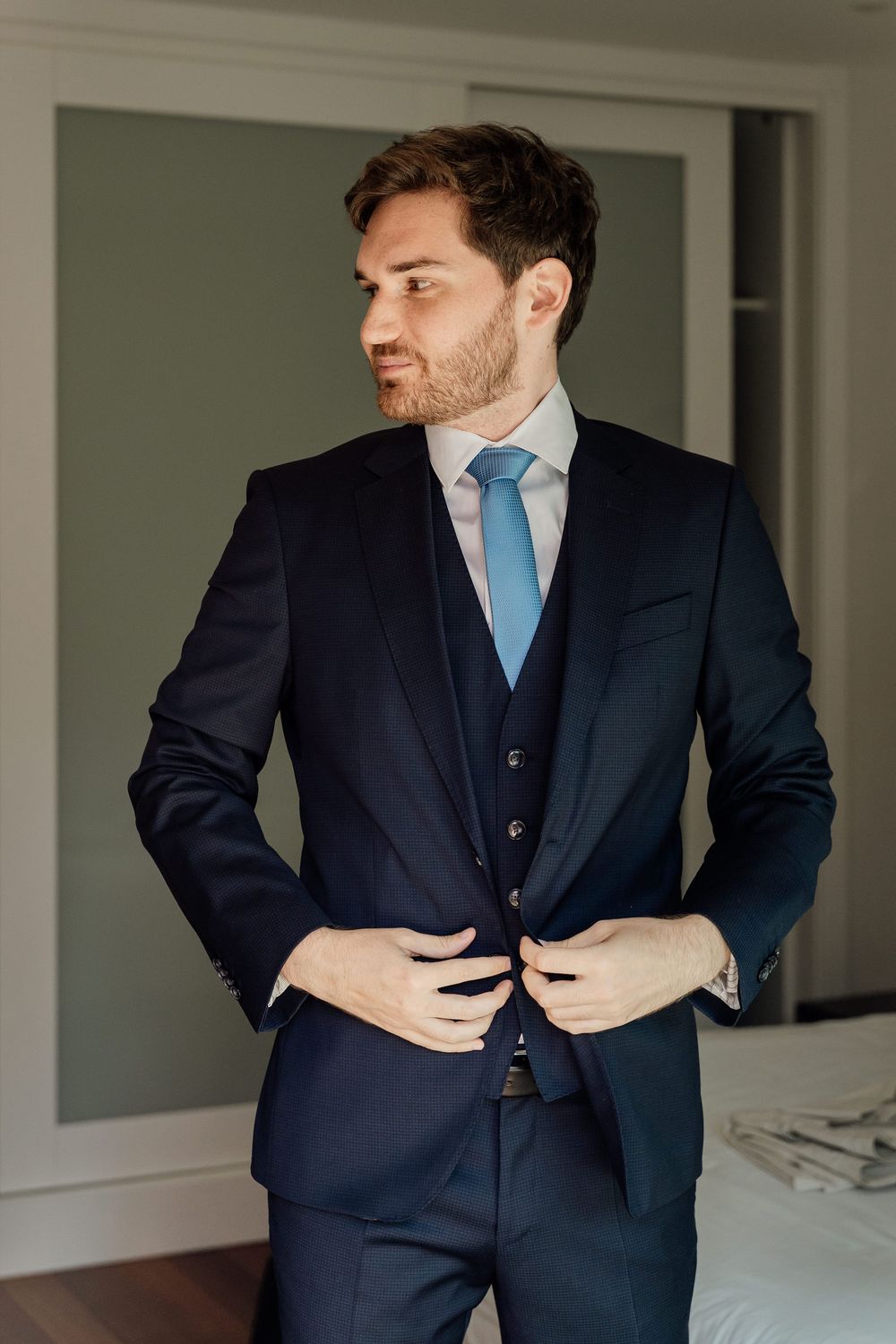 A series of photos showing details of a navy blue suit with light blue tie being adjusted.