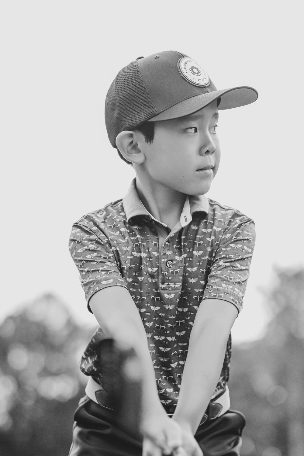 Young baseball player in cap and polo shirt looking to the side.