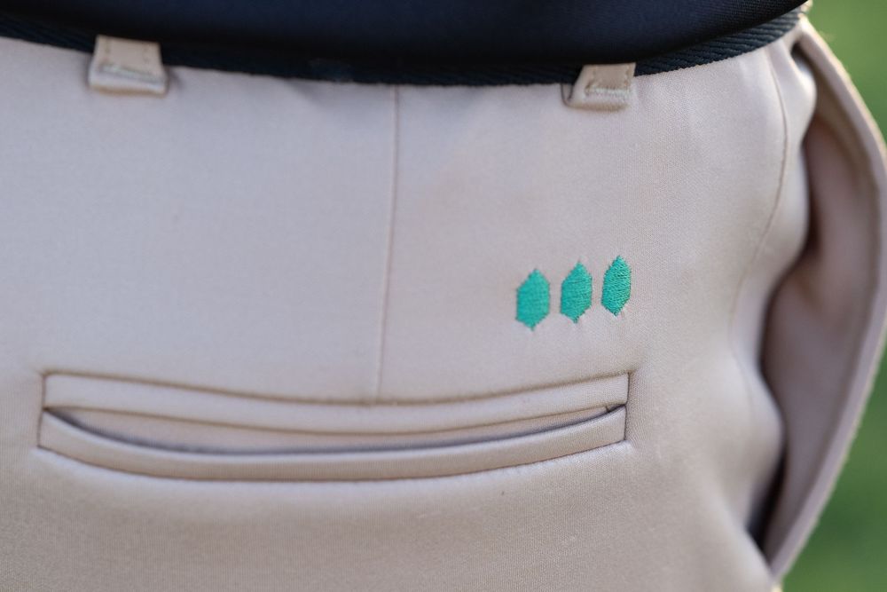 Close-up detail of white baseball pants with turquoise embroidered dots.