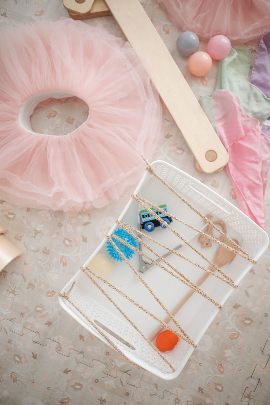 Pink tulle tutu and hair accessories displayed with blue butterfly clips on a white tray against a textured background.
