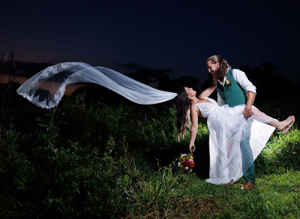 A flowing white wedding dress captured in outdoor nature settings at dusk.