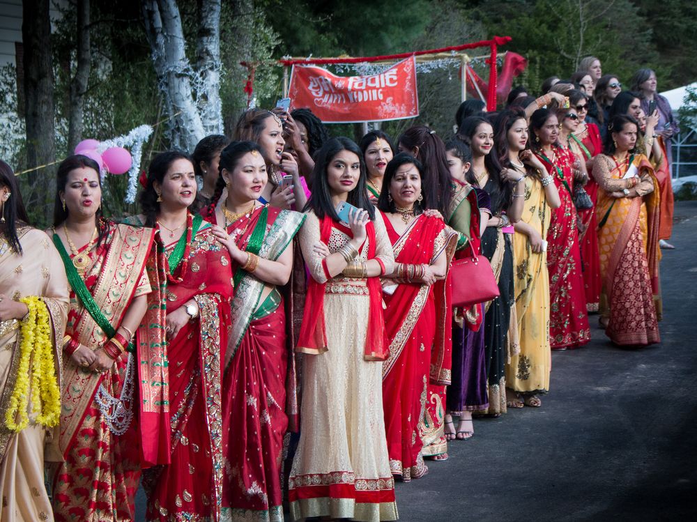 Large group of women in colorful traditional Indian saris and dresses gathered outdoors for a cultural celebration.