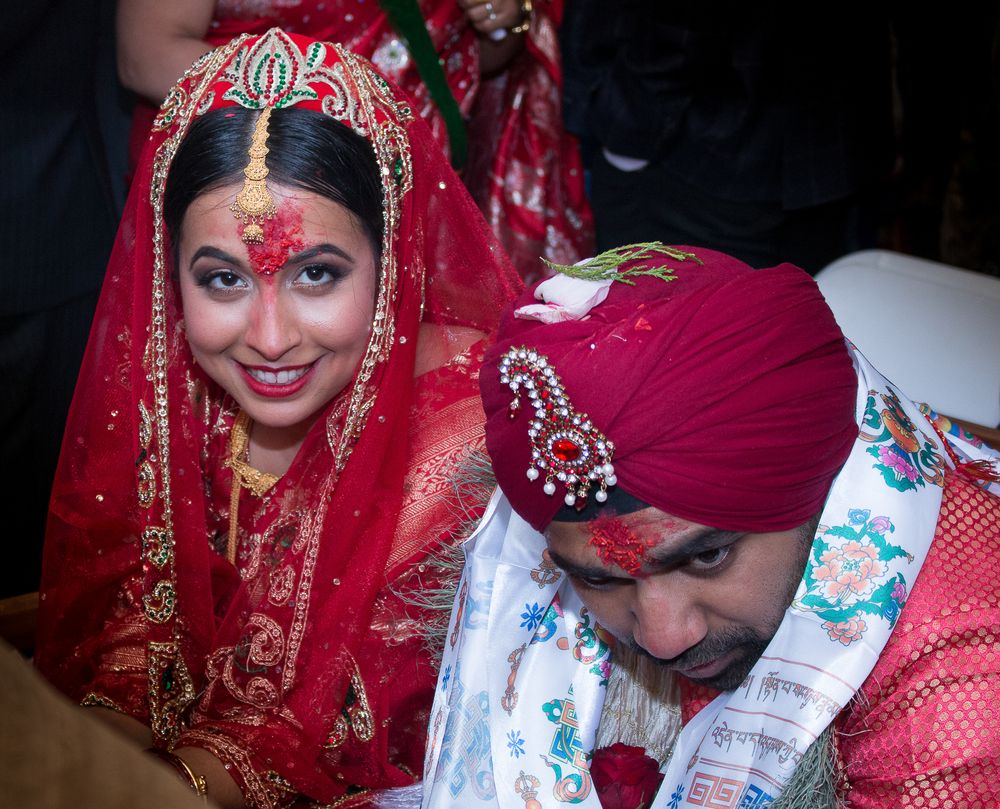 Traditional Indian wedding ceremony showing signing of marriage documents with red and gold decorations.