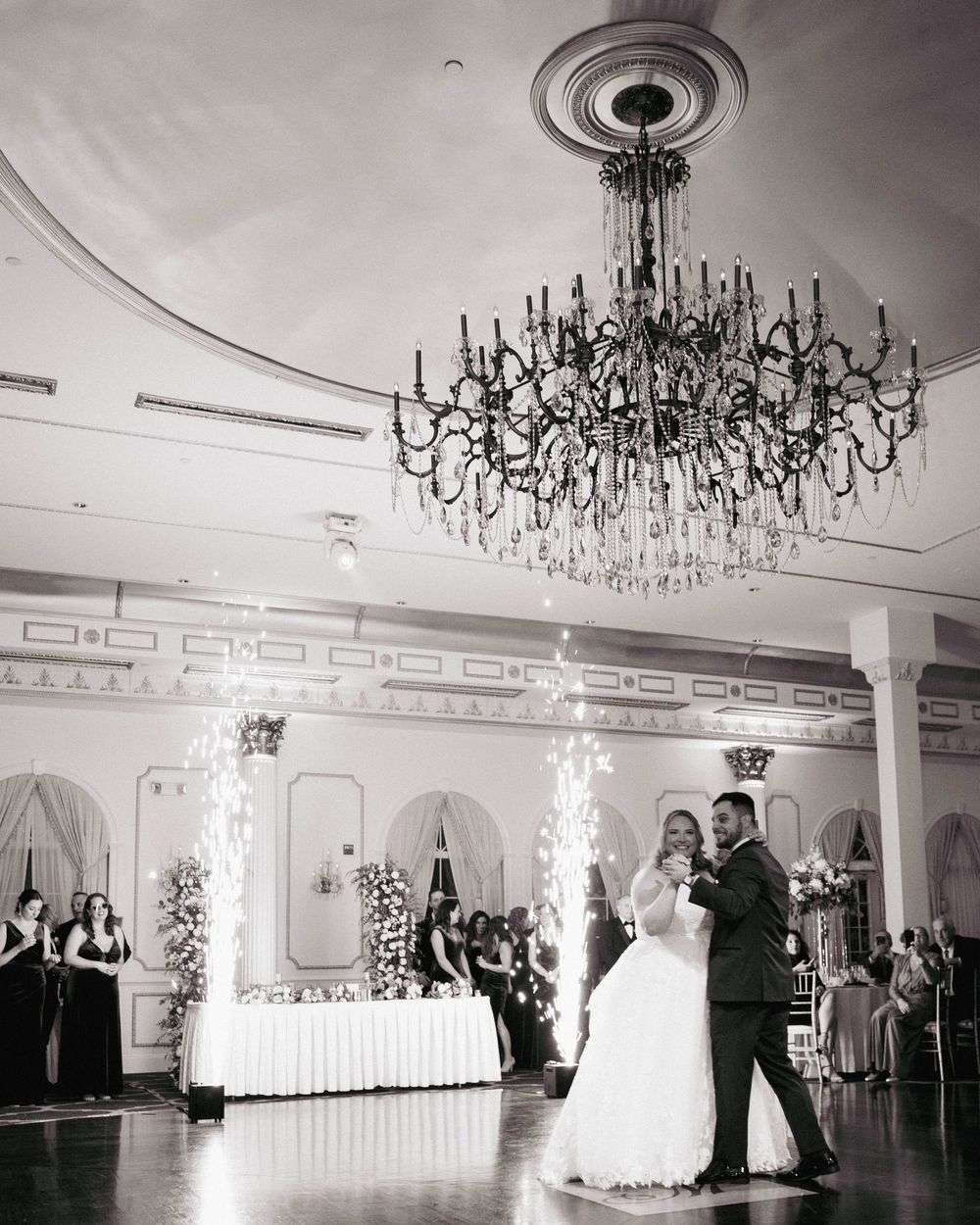 Elegant ballroom wedding reception with crystal chandeliers and couples dancing.