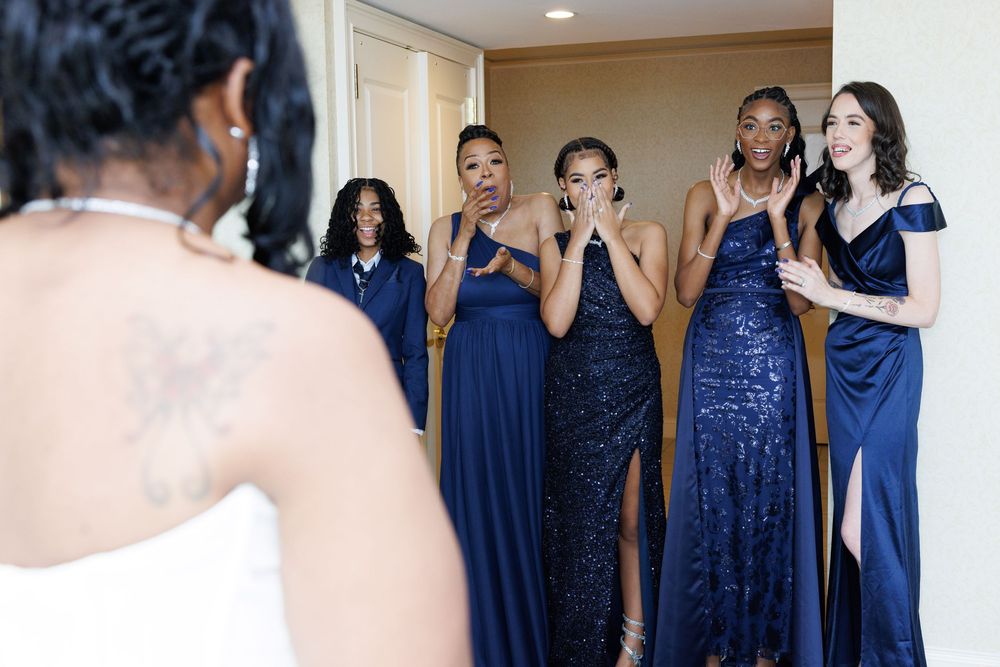 Bridesmaids wearing elegant navy blue dresses pose together at a formal wedding event.