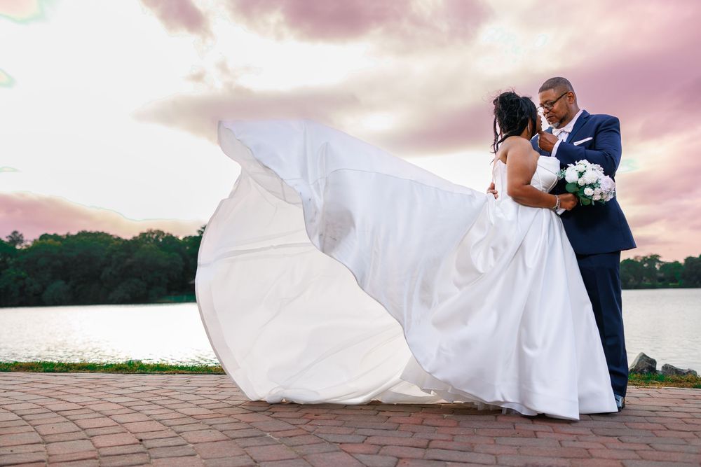 Romantic sunset wedding portraits with flowing dress against pink sky.