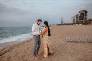 Tender cuddle between a couple on the empty beach in Badalona, Spain, lit by the first soft light of the day