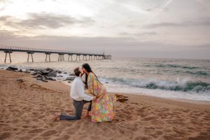 Playful couple piggyback ride on the vast golden sands of Badalona Beach during a joyful sunrise photo shoot