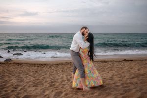 Candid couple snapshot running towards the waves on empty Badalona Beach during an intimate sunrise session