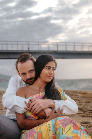 Laughing couple holding hands against the empty coastal horizon of Badalona Beach during a golden hour shoot