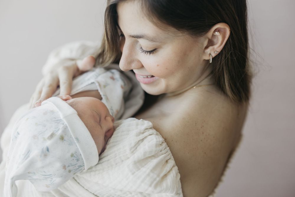 A tender moment captured in black and white as a parent holds their sleeping baby against their chest.