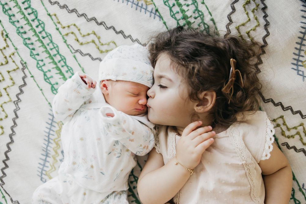 Two young children sleeping peacefully together on a patterned blanket.