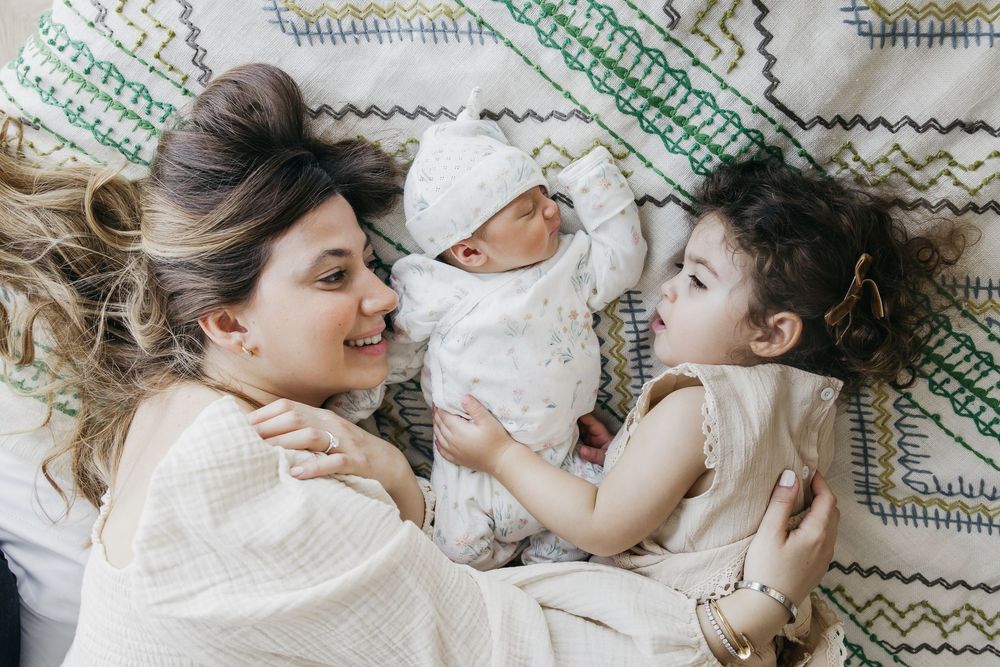 Mother and baby lying together on a patterned blanket while sharing tender moments and cuddles.